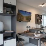 Kitchen with dining table, TV, and shelves. Modern furnishings with white and gray furniture.