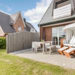 Terrace with lounge chair, table and chairs next to a house with sliding door.