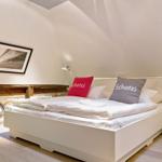 Schlafzimmer mit weißem Bett, rotem und grauem Kissen, Nachttisch und Wandbild.
