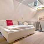 Schlafzimmer mit Dachschrägen, Bett, Nachttisch und Fenster