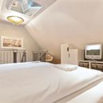 Schlafzimmer mit Dachschrägen, Bett, TV und Kleiderschrank.