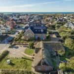 Dorf mit Häusern, Grünflächen und Blick aufs Meer