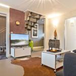 Wohnzimmer mit Fernseher, Couch und Treppenhaus.
