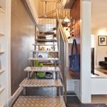 Treppenhaus mit Metalltreppe und Bücherregal. Wohnbereich mit Sofa und Fernseher.