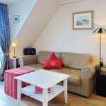 Living room with sofa, table, and window. Sloped ceiling and curtains visible.