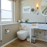 Bathroom with toilet, sink, and window. Tiled wall and wooden floor.