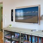 TV with beach scene, speakers, table lamp, and bookcase