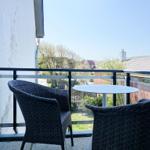 Terrace with table and two chairs, view of garden and rooftops.