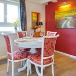 Red wall art above dining table with four chairs and window.
