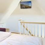 Bedroom with sloped ceiling, bed, and TV mounted on the wall.