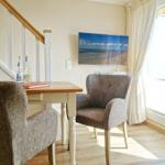 Dining table with two chairs, TV, and window with curtains.