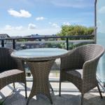 Terrace with table and two chairs. View of residential area and sky.