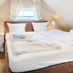 Double bed with white linens and two nightstands under sloped ceilings.