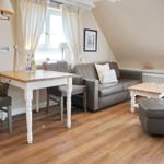 Living room with sofa, table, and window. Wooden floor and cream-colored walls.