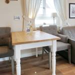Wooden table with two chairs and sofa in room with window.
