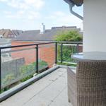 Terrasse mit Tisch und Stühlen, Blick auf Wohnhäuser und Grünflächen.