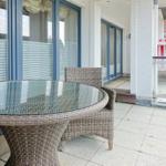 Terrasse mit runden Tisch und Stühlen, Glasfront und rotem Strandkorb