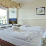 Schlafzimmer mit Doppelbett, TV und Balkonansicht.