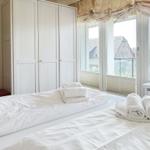 Zwei Betten mit weißen Laken und Handtüchern. Große Fenster mit Blick auf die Straße.
