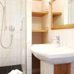 Badezimmer mit Dusche, Waschbecken und Spiegel