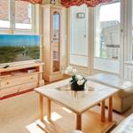 Wohnzimmer mit TV, Holzmöbeln und Blick auf Balkon