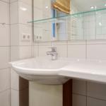 Sink with mirror and glass shelf in white tiled wall