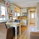 Kitchen with dining area, wooden floor, and window with curtains