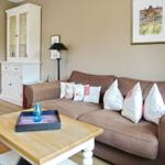 A living room with a brown sofa, cushions, and wooden table.