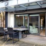 Deck with table, chairs, and wood railing. Glass door opens into the house.