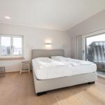 Bedroom with bed, window, and glass door to terrace.