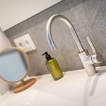Sink with modern faucet and green liquid soap dispenser.