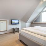 Bedroom with sloped ceiling, bed, TV, and window.