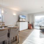 Dining area with table and chairs, TV, and seating in living area.