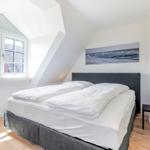 Schlafzimmer mit Doppelbett, Fenster und Wandbild.