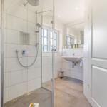 Badezimmer mit Dusche, Waschbecken und Fenster
