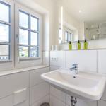 Badezimmer mit Waschbecken, Spiegel und Fenster zur Aussicht.