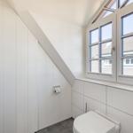 Badezimmer mit Toilette, Fenster und Heizkörper an der Wand.