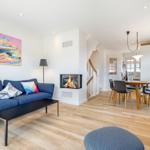 Wohn- und Essbereich mit Kamin, Sofa und Holzboden.