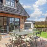 Terrasse mit Tisch, Stühlen und Liegestuhl. Hinterhof mit Steinmauer und Holzzaun.