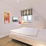 Schlafzimmer mit Doppelbett, Fenster und Kunstwerken an der Wand.