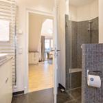 Badezimmer mit Dusche, Waschbecken und Blick in Wohnbereich.