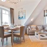 Wohn- und Essbereich mit Sofa, Tisch und Stühlen unter Dachschrägen.