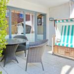 Terrace with garden furniture and beach chair with green-white stripes.