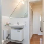 Bathroom with shower, sink, and mirror. Wooden floor and towel warmer.