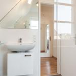 Bathroom with sink, mirror, and shower. Passage to the apartment.