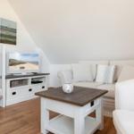 Living room with sofa, TV, and table under sloped ceiling