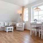 Living and dining area with sofa, chair, table, and windows.