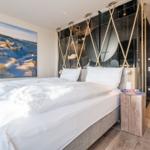 Schlafzimmer mit Bett, Wandbild und Holzboden