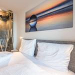 Schlafzimmer mit Doppelbett, Dusche und Wandbild.