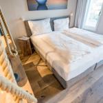 Schlafzimmer mit Doppelbett, Holzboden und Fenster. Seil als Dekoration sichtbar.